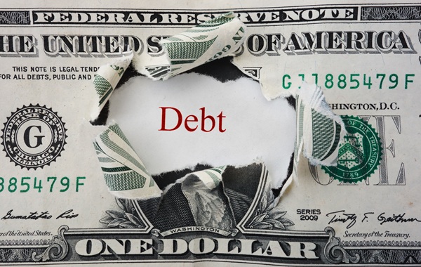 Torn dollar bill revealing the word “Debt” printed in red underneath.